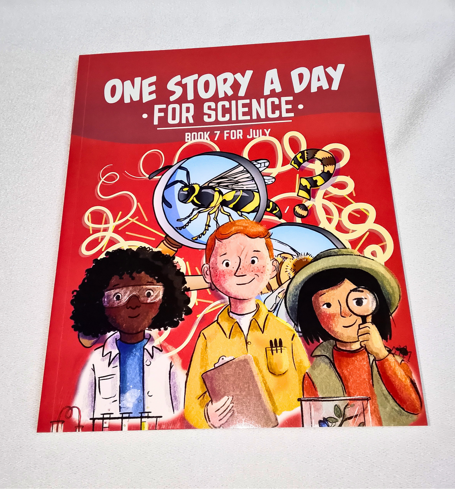 Book titled 'One Story a Day for Science' with illustrations of children and a bee on a red background.