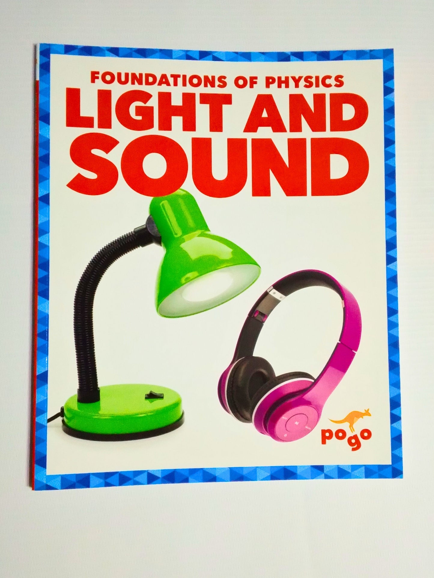 Book titled 'Foundations of Physics: Light and Sound' with a green lamp and pink headphones on the cover.